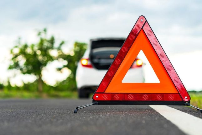 Problems car and a red triangle warning sign on the road